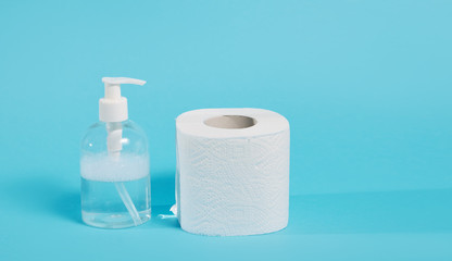 Stock of soft white toilet paper and liquid antiseptic in a transparent bottle on blue background. In case of a virus outbreak