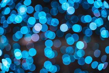 Blurred blue city lights against dark evening sky. Abstract background with urban bokeh