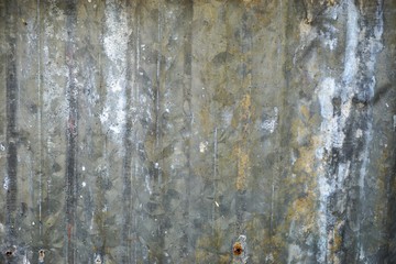 Weathered corrugated metal with spatters of paint and random discolored patches soft focus horizontal background texture