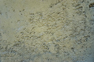 Faded yellow paint on rough concrete wall surface