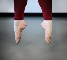 Airborne ballet dancer, in pink pointe shoes, mid-jump in sauté © DGC