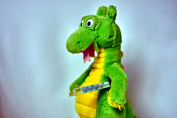 Plush toy dinosaur with a traditional thermometer.