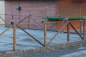 brown decorative wooden fence made of planks with a row of round lanterns on the street