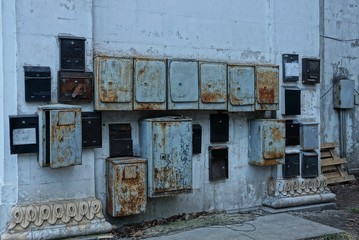 Fototapeta na wymiar a lot of old gray and black iron mailboxes in rust on a concrete wall in the street