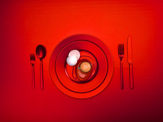 Scarlet dishes with a broken egg and shell on a plate. Ceramic dishes with a fork, spoon and knife. For cafes, posters, breakfasts and dinners. Copyspace for your individual text