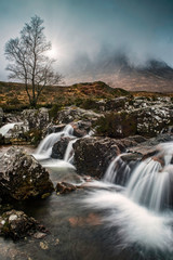 Glencoe, Scotland - Jan 2020: The rising sun lights the clouds above the mountain peaks at Glencoe in the Highlands of Scotland