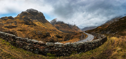 Glencoe, Scotland - Jan 2020: Panpramic view along a mountain road on the 3 sisters as a winter storm passes overhead