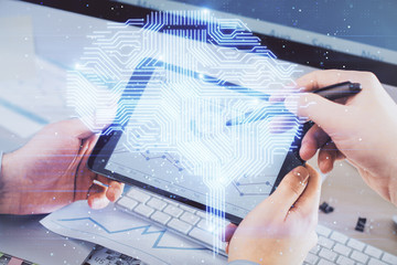 Double exposure of man's hand holding and using a digital device and brain hologram drawing. Data concept.