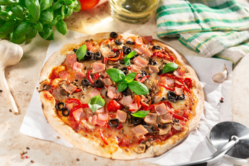 Tasty homemade pizza with ham, black olives and red pepper