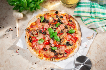 Tasty homemade pizza with ham, black olives and red pepper