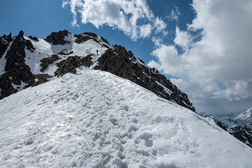 A path in the snow leading to the top of the mountain with the sky above