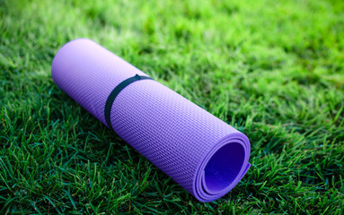 Close up Yoga mat roll on green grass ready for practice and relax with yoga,Recreation Concept