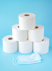  Toilet paper stacked rolls, medicine mask on a blue background. Items that buiyng in panic. Toilet paper crisis due to coronavirus COVID-19 quarantine. Copy space