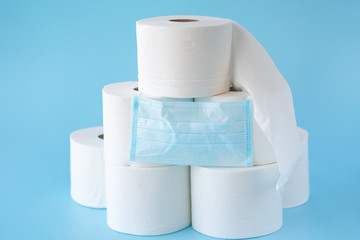  Toilet paper stacked rolls, medicine mask on a blue background. Items that buiyng in panic. Toilet paper crisis due to coronavirus COVID-19 quarantine. Copy space