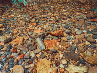 Forest river stones in shallow river with clarity water. Close up of stones in pure fresh transparent mountain river water