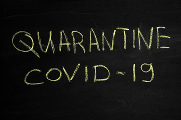 The inscription Quarantine and covid19 on a black board. Yellow chalk