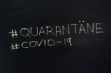 The word is in German quarantine hashtag. The text on the chalk Board. Yellow chalk.