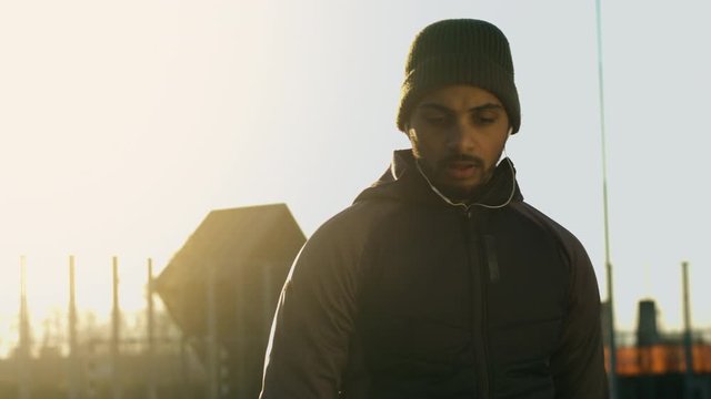 A portrait of a Native American sportsman breathing and looking into the camera while listening to music, filmed in slow motion