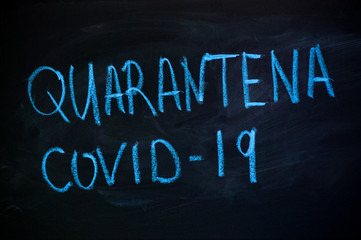 word Quarantine and covid19 in Italian on a black board. Blue chalk