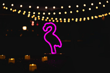 pink flamingo lamp at night with candles and bokeh background