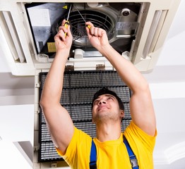 Repairman repairing ceiling air conditioning unit