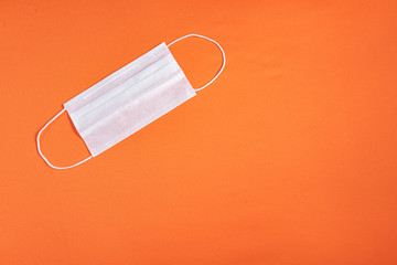 Surgical mask over minimalist orange background