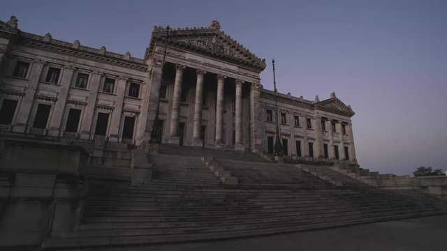 Toma con gimbal del palacio legislativo de Montevideo realizando suave acercamiento durante la hora azul