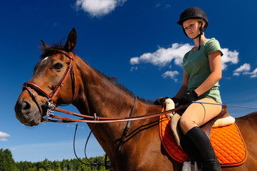 Female rider mounted on her thoroughbred horse outdoors before a training session
