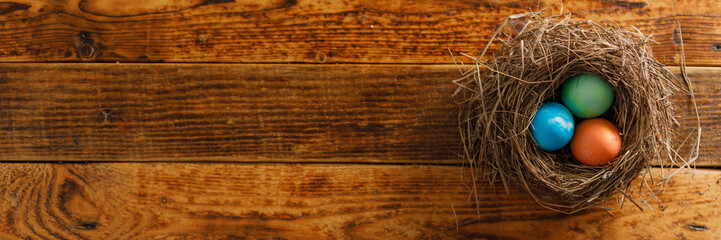 Still life of easter eggs in a bird's nest on a wooden background. Rustic. Easter celebration concept. Copy space. Flat lay. Banner.