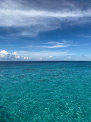 Landscape. View of the blue ocean from the line of the beach. Beautiful natural background. Horizon line of blue sea and sky with clouds. Vertical, cropped image, free space, nobody. Tourism concept.
