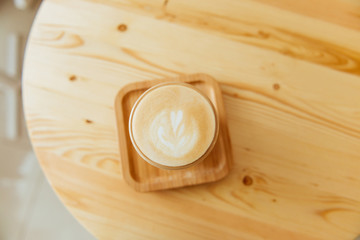 A beautiful cup of cappuccino with latte art in the wooden space background. Trendy toning.