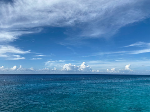 Landscape. View of the blue ocean from the line of the beach. Beautiful natural background. Horizon line of blue sea and sky with clouds. Horizontal, cropped image, free space, nobody. Tourism concept