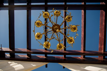 Obraz premium Low Angle view of a golden chandelier on a wedding set up with blue sky background