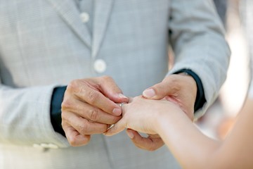 Groom putting a ring on the bride's finger during the wedding ceremony.