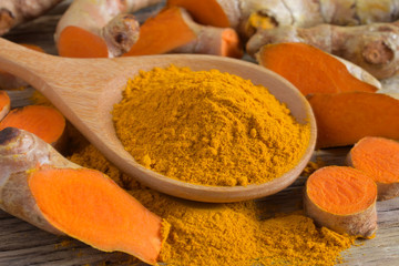 Turmeric powder and fresh turmeric (curcumin) on wooden background,Used for cooking.