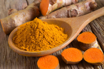 Turmeric powder and fresh turmeric (curcumin) on wooden background,Used for cooking .
