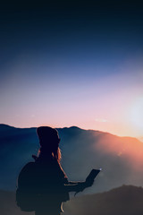 Young woman looking at a map with morning in mountains background.