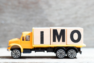 Truck hold letter block in word IMO (Abbreviation of in my opinion) on wood background