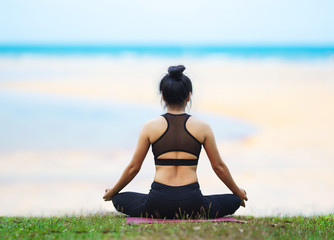 Young asian woman meditation in a yoga pose above the beach in the morning with beautiful sea in tropical island. Comfortable ,Relax ,Vacations , Healthy and Yoga Concept