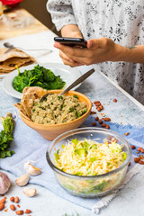Smartphone food photo of food. Phone cooked quinoa, fresh detox salad photography. Vegan lunch, vegetarian dinner. Woman hands, kitchen table or cafe. For social media or blogging concept.