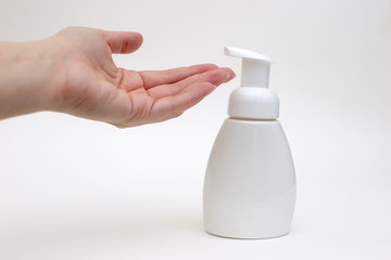 Hand on a white background with a white bottle of antibacterial soap