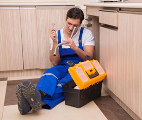 Young repairman working at the kitchen