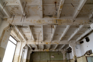 Photo of a dirty white ceiling in an abandoned factory under the light from the window