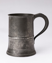 An old antique 19th Century hallmarked  English pewter beer tankard on a white background.