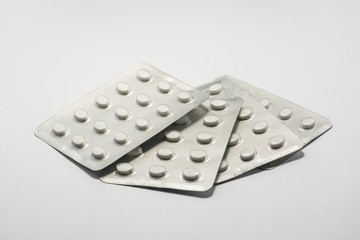Foil packets of white tablet pills medication on plain white background. Cure and treatment concept.