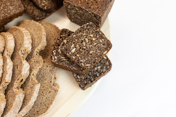 On a white background are cut pieces of white and black bread. Whole grain bread with seeds, the concept of a healthy diet, organic food, farm products. free space for text.