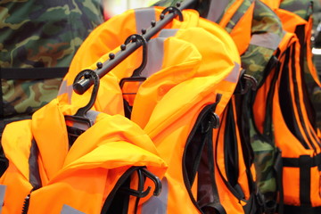 A lot bright yellow marine life vest jackets on hangers close up, safety on water tourism activity and watersports