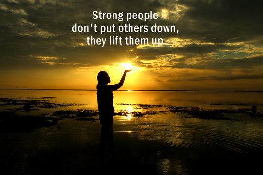 Inspirational motivational quote - Strong people do not put others down, they lift them up. With silhouette of woman standing and  holding the sun light on  the beach at sunset.