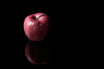 Red Apple on black background with water drops