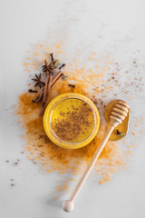 Fototapeta premium Golden milk with turmeric powder in a glass on a light background, copy space. Health and energy, anti-flu, natural fighting drink. Clean food, detox, weight loss concept.